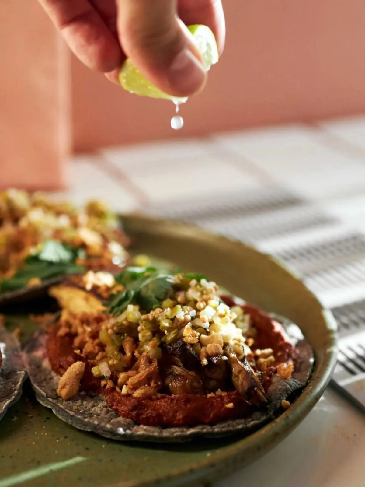 O mână stoarce lime peste un taco